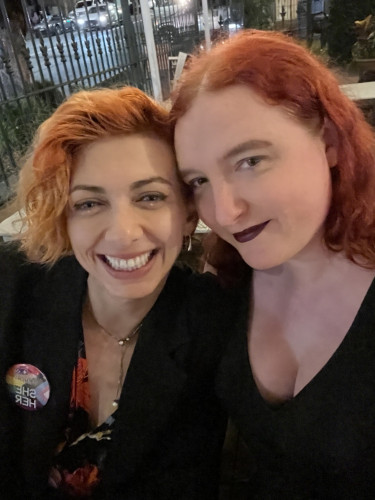 It me and my girlfriend. We both have artificially dyed hair, variations on red. She has a barely-visible side-shave and a she/her badge. I mean honestly, I could describe more but it feels weird.
