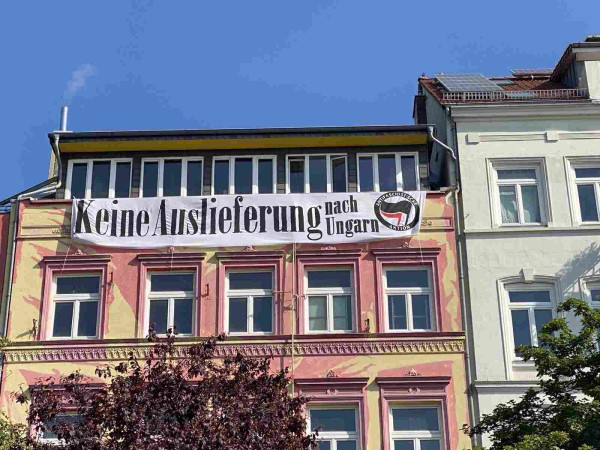 An einer Hauswand in Hamburg, St Pauli, hängt von einem Balkon ein Banner auf dem groß "keine Auslieferung nach Ungarn" steht. Daneben ein Antifa Symbol. 