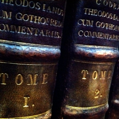 Three antique leather volumes on a shelf. They are three volumes of Codex Theodos Cum, labeled TOME 1, TOME 2, TOME 3–4. Taken at the Royal College of Physicians Library, Regent's Park, London, UK.