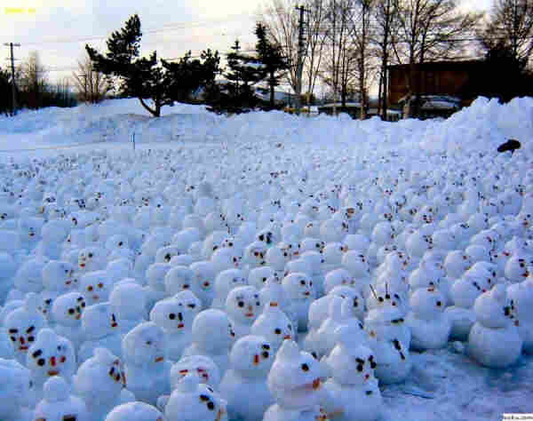 A snowscape with what looks like several hundred small 'snowmen'  and they look real, as though someone actually made them. Not AI generated.