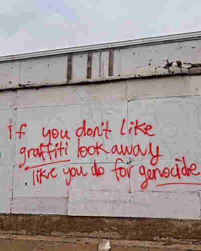 'If you don't like graffiti look away  like you do for genocide" written on a wall with red spray paint