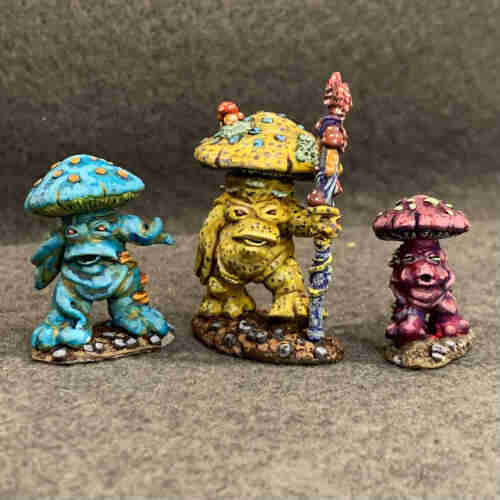 Three mushrooms with arms and legs walking forward. The center one is yellow with purple dots and light green lichen, holding a fungus-covered staff. The left one is turquoise with orange lichen. The right one is magenta with light green lichen. They all have beady eyes and large overbites. They all walk on red-brown earth with gray stones. 