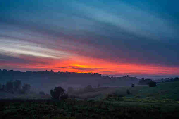 red sunrise behind rolling hills at dawn in portugal