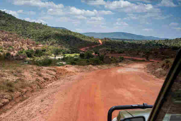 Photo of a red dirt track making turns in hills covered with low vegetation