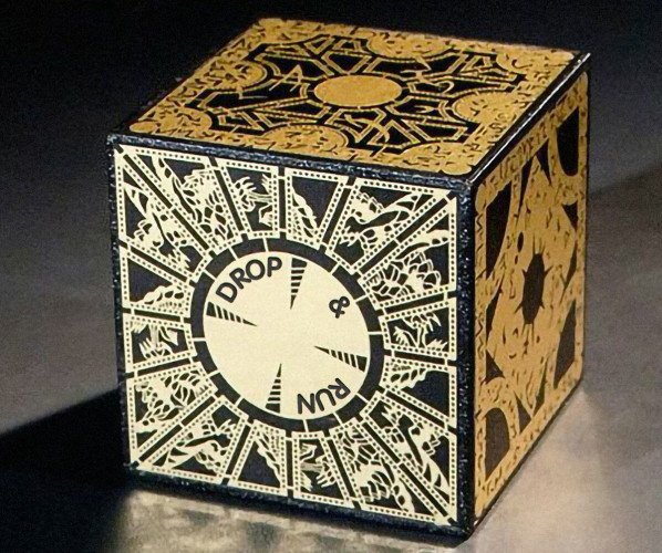 A picture of a puzzle box, in black with archaic and mystical gold inlaid symbology. It looks a little dangerous. On a circular dial on the front in a suspiciously modern possibly 1950s or 60s etched font is the text DROP & RUN