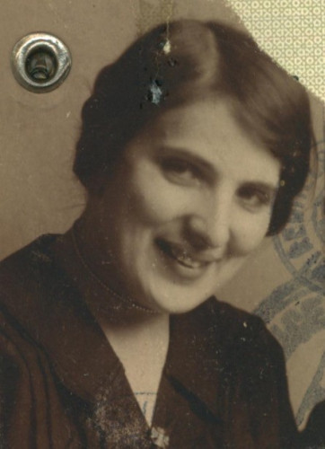 Vintage portrait of an woman smiling, set against a patterned background, showing historical attire and hairstyle characteristic of the early 20th century.