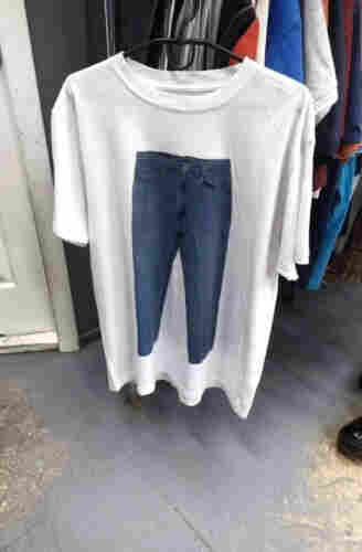 White t-shirt with a picture of a pair of jeans on the front.