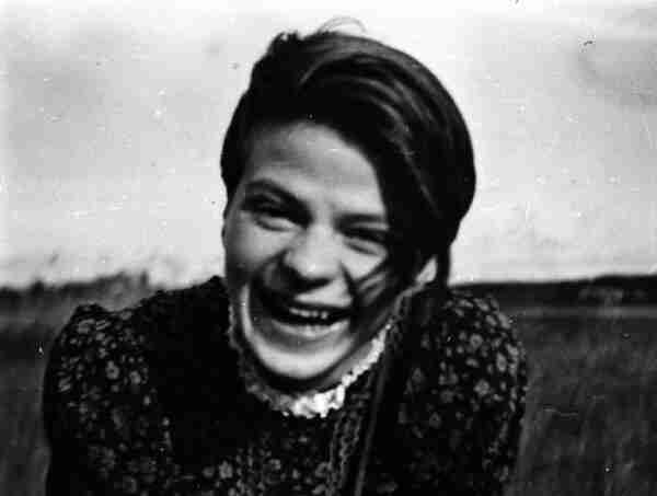 snapshot of Sophie Scholl, laughing. She is a white woman with dark hair.