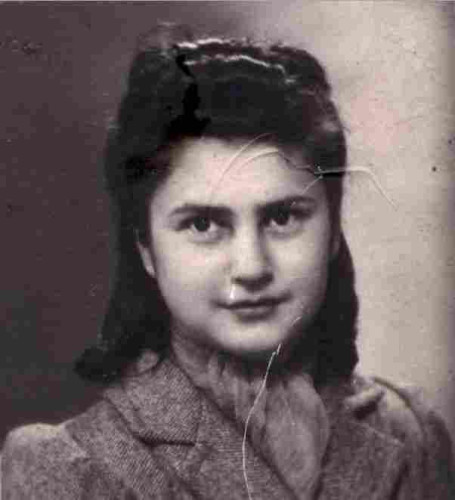 A portrait photo of the face of a teenage girl. She has long dark hair falling behind her head onto her shoulders. She is wearing a coat and has a scarf on her neck.