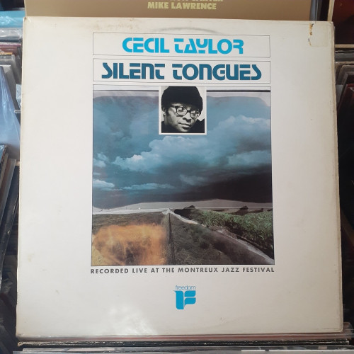 Album cover features a photograph of dark storm clouds over a distant hill.  In the foreground there are green fields.