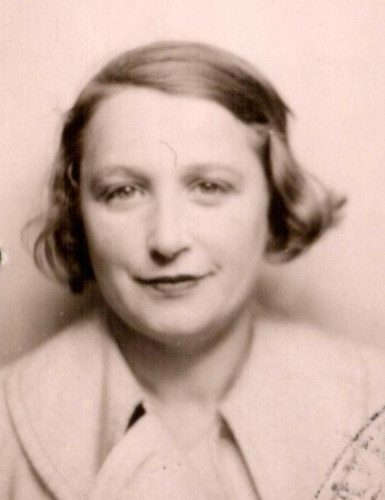 Vintage black-and-white passport photo of a woman with a gentle smile, wearing a light-colored jacket.