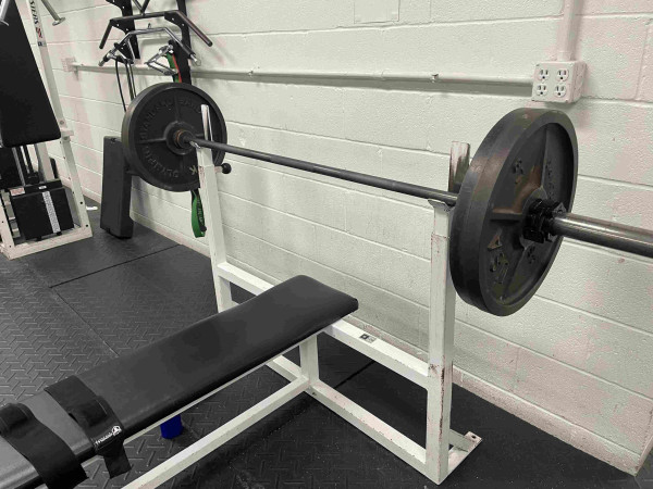 A weight bench holding a barbell loaded with weights