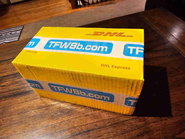 Yellow DHL Express shipping box sealed with TFW8b.com packing tape. 