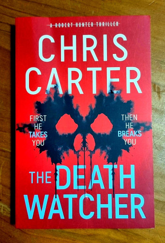 Cover of book by Chris Carter
Title : The Death Watcher
Cover is red with author name in white & book title in light blue.
There is a stylised partial skull of eyes and nose in dripping black paint.
The words - First he takes you     Then he breaks you
