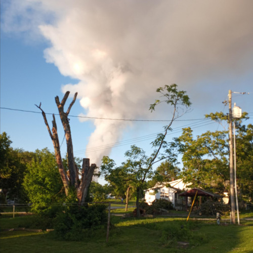 Photo of an unfenced yard and a large plume of smoke blocking most of the sky