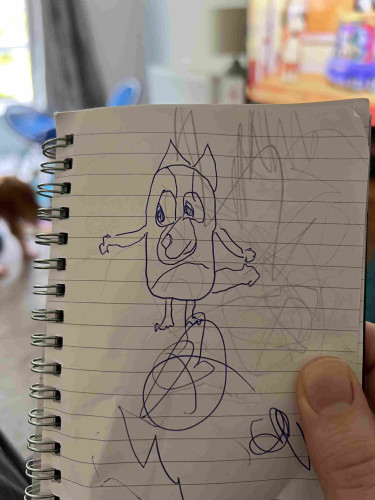 Hand drawn picture of the cartoon character Bluey in a note pad, the actual show playing in the background