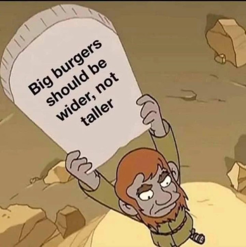 A man with a balding head and beard is holding a sign that says, 'Big burgers should be wider, not taller.'.