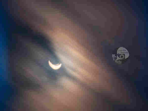 a long exposure of the April solar eclipse. It is a partial eclipse, partly covered by lightly colored, streaking clouds. There is a slight doubling effect due to camera movement
