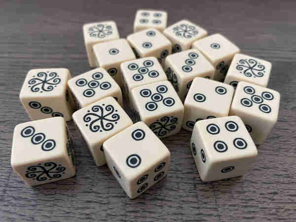 Photo of Vaesen dice, which are six-sided dice with regular numbers on 5 sides, but the 6 is a special swirly symbol indicating success.