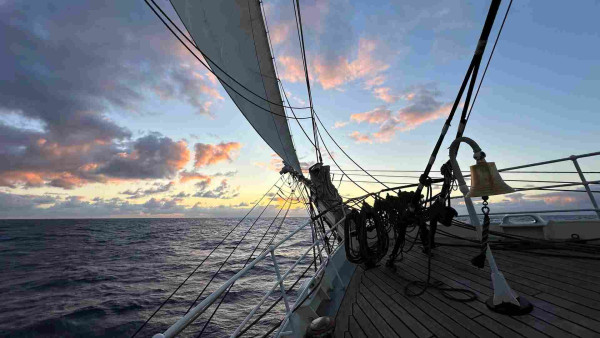 Sunset viewed through the jib boom and fore sails of a ship. 