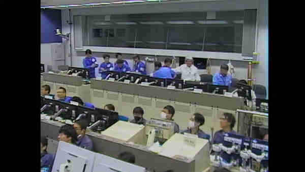 Photograph from the live feed showing the control room, with people shaking each others hands.