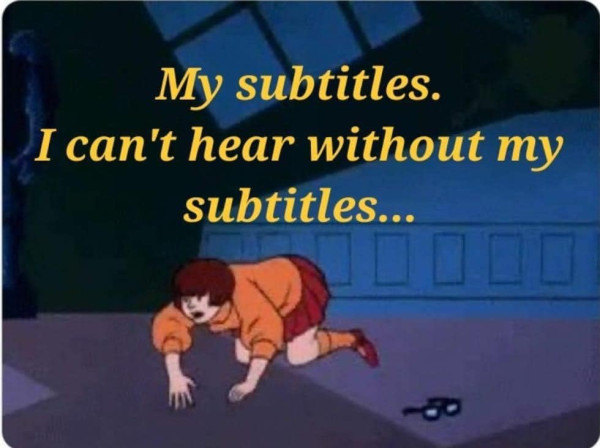 Velma from Scooby-Doo is shown searching for her glasses. A caption reads, “My subtitles. I can’t hear without my subtitles…”.