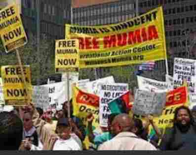 Demonstrators with yellow signs that read: Free Mumia Now!