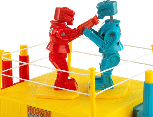 An old plastic toy called "Rock 'Em Sock 'Em Robots." Two plastic figures, each one a different color, stand facing each other in a boxing ring. One figure has punched the other one in the jaw so that its head has popped up.