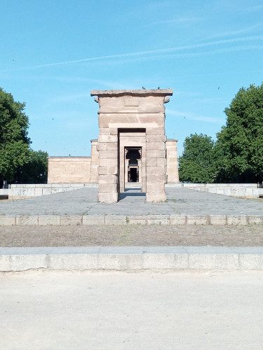 My photo of Templo de Debod, an Egyptian temple that was given to Spain to say thank you for its help in rescuing the temples and monuments from being underwater when the Aswan dam was constructed.
There are 3 stone arches as a gateway before the stone temple which can be seen behind as a low square building