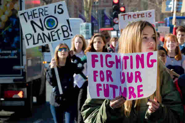 Young people, marching at a climate rally. They are holding signs that say: "There is No Planet B" and "Fighting For Our Future."