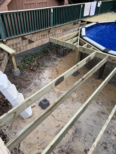 Deck under construction.  Several new joists can be seen as well as the joist work erected around the edge of the pool.