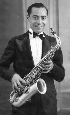 A vintage black and white photo of an individual in formal attire with a bow tie, holding a saxophone and smiling at the camera.