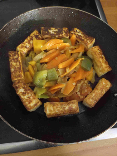 Photo of a large frying pan with wok fried veg in the middle and tofu around the outside. It includes carrot, garlic, pepper, onion and tofu sauce 
