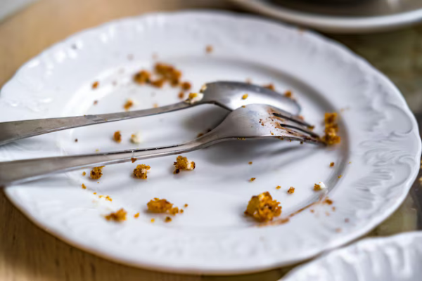 Empty plate with waffle crumbs, a fork, and a spoon