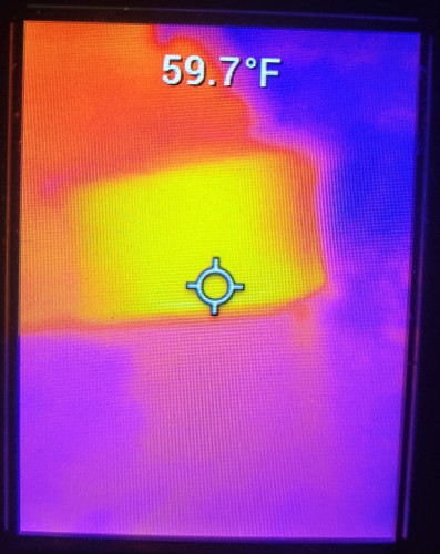 Glowing rectangular box seen on FLIR, behind a building and many colder objects and trees nearby