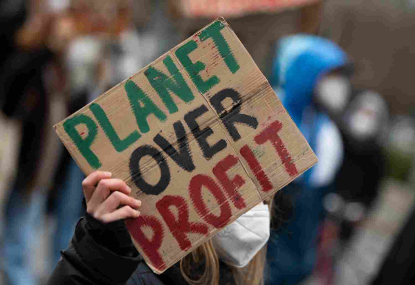 At a demonstration of the climate activists Fridays For Future, a participant carries a placard with the inscription "Planet over Profit."