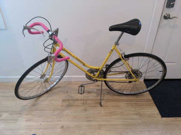 A 1973 Schwinn Varsity step-through bicycle in Kool Lemon yellow.
