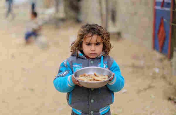 stock image of a Palestinian child carrying small plate with bread