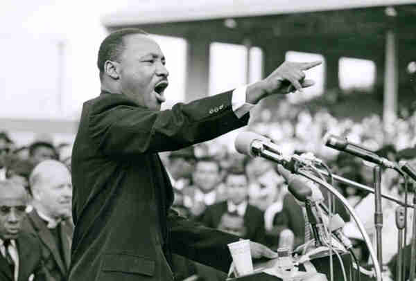 MLK giving a speech, pointing forward from a podium