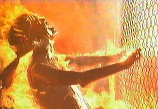 screenshot from terminator where a person holds onto a fence and burns as a nuke blows them away