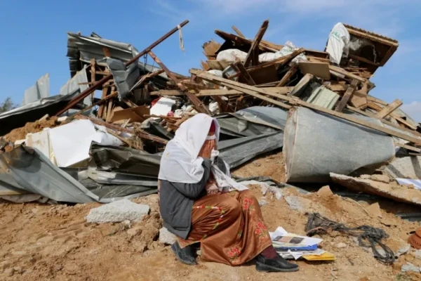 An Arab Israeli woman sits next to ruins of her home that was destroyed by Israeli bulldozers in Umm al-Hiran, on January 18, 2017 [Ammar Awad/Reuters]