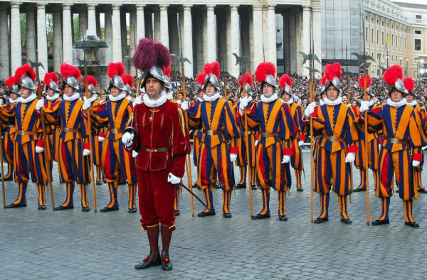 Photo of members of the Swiss Guard, who orotect the Vatican. They look like the lords-a-leaping from that Christmas song, or jesters with big budgets. Fancy outfits with parachute capris and red feathers coming out of their tin helmets 