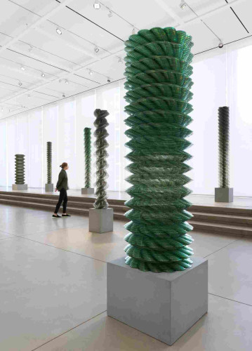 in a gallery space, twisting sculptures made from stacked CDs tower high above a viewer
