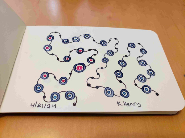 Hand drawn generative art in ink on an open page of my sketchbook. The abstract pattern looks a bit like beads on a string.