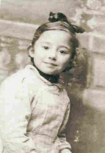 A photo of a young girl with the hair tied with a bow. She is looking into the camera. 