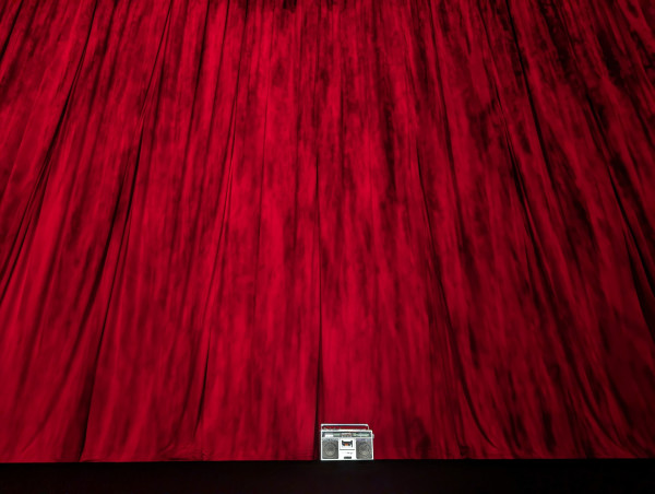 A boom box in a spotlight on a black stage with a red curtain backdrop. 

It's the pantages theater screening of Stop Making Sense.