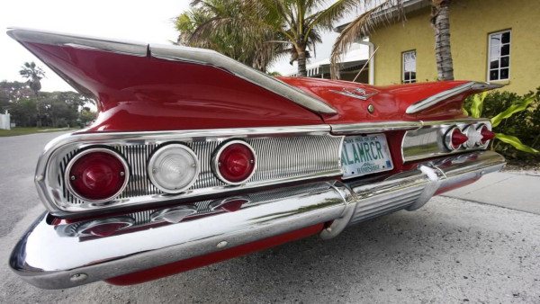 Color photograph. 
Tail fins on the back end of a vintage red Chevrolet from the late 1950s.
Use of a wide-angle lens exaggerates the size of the enormous fins.