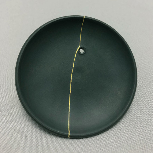 Black lid of a Kyusu teapot. Underside. A golden seam runs across the lid where the lid was once broken.