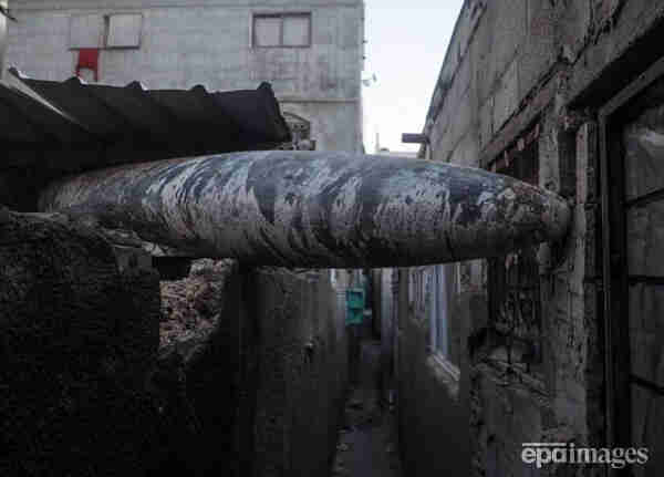a bombs that failed to detonate is sitting between 2 houses in Gaza