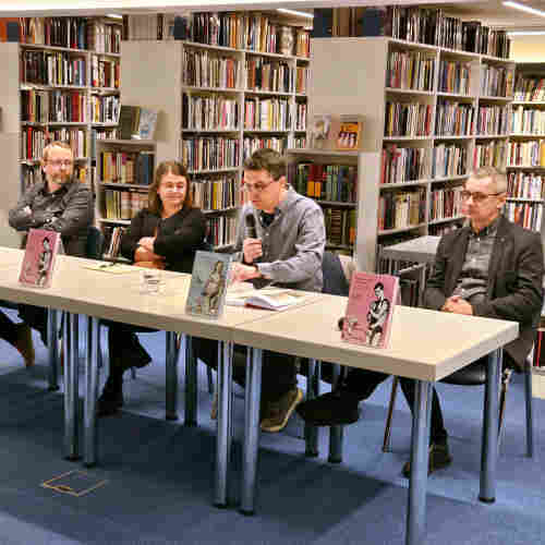 Marko Zubak, Anita Buhin, Igor Duda, and Damir Agičić sitting behind a table in a bookstore. On the table, the English and Coratian editions of the book are showcased.